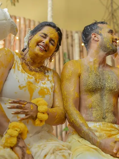 The couple getting drenched in blessings and water during their outdoor Haldi ceremony.