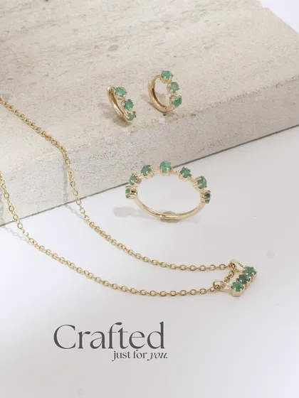 The full Petit Emerald trio: a necklace, ring, and huggie earrings. This set proves that small, delicate pieces can make a major impact.