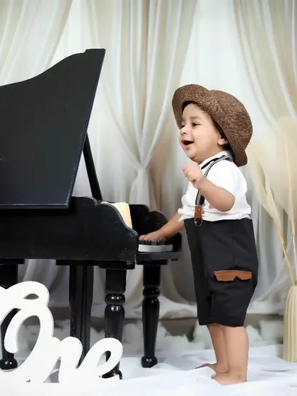 This little musician is standing and playing the piano, full of energy and smiles.