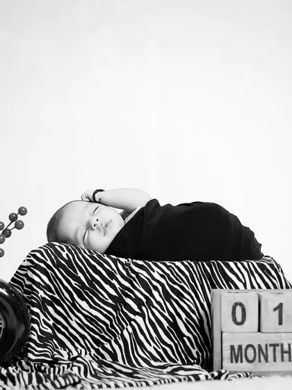 A black and white version of the one-month milestone shoot, offering a timeless and artistic feel. The high contrast emphasizes the baby's peaceful expression.