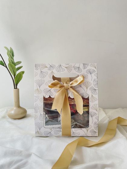 The beautifully designed Mini Rakhi Hamper box, featuring a delicate pattern and a golden ribbon.