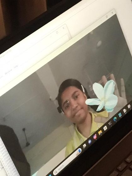 A student smiles as she successfully implements an AR filter, placing a digital flower in her hand. This fun, interactive project makes complex AI concepts accessible and engaging.