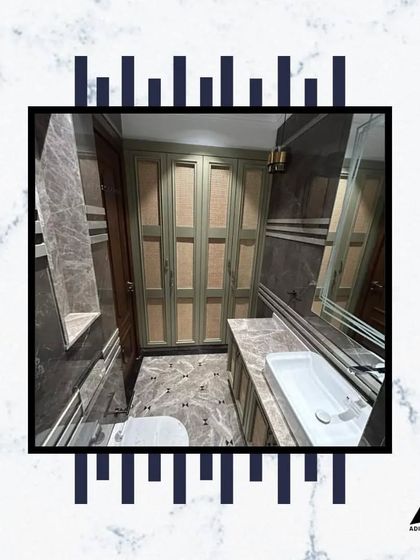 A well-designed bathroom with ample storage. The built-in wardrobe and vanity are finished in a soft green-grey, providing a subtle pop of color against the grey marble floor and walls.