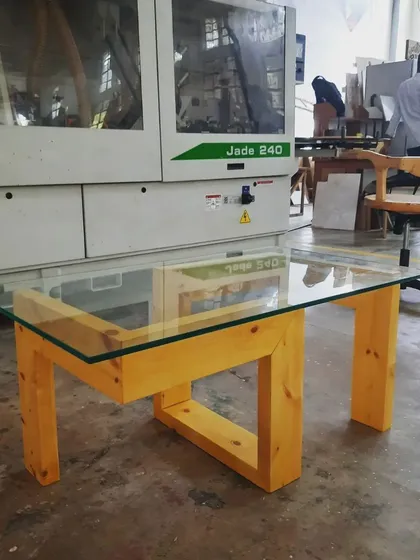 A classic glass-top coffee table with a modern, interlocking base design. This project taught students how to create a stable structure with open, geometric forms and prepare it for a non-wood element like a glass surface.