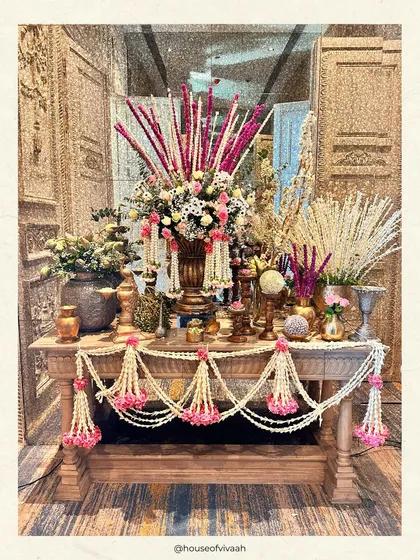 A beautifully styled console table with traditional floral garlands and brassware, showcasing the detailed and heritage-inspired elements of the decor.
