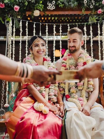 An elder offers blessings to the couple as they sit on the floral swing, a sweet and meaningful part of the ceremony.