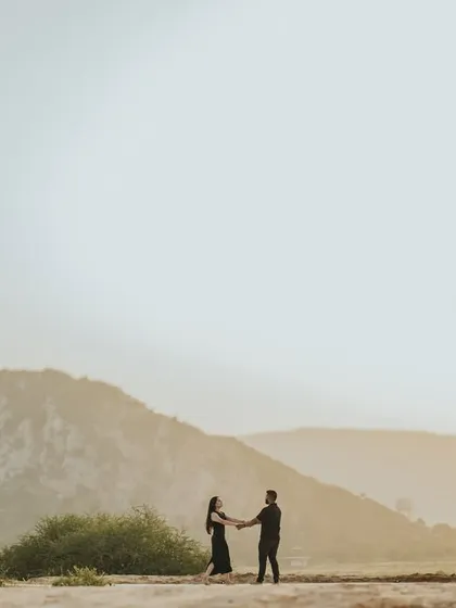 A wide shot of the couple holding hands against the backdrop of a mountain. This image emphasizes the feeling of starting a new journey together in a vast, open landscape.