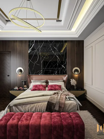 This master bedroom in JP Nagar features a striking back wall with fluted panels and black marble, complemented by a rich maroon bench and herringbone wooden flooring.