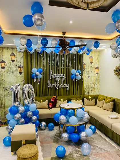 A 10th birthday party in a living room with a blue and silver theme, including ceiling balloons and number foils.