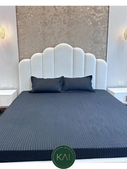 A close-up of the white scalloped headboard, showing the detail of the vertical tufting. This design adds a touch of softness and sophistication to the bedroom, creating a comfortable and stylish backdrop.