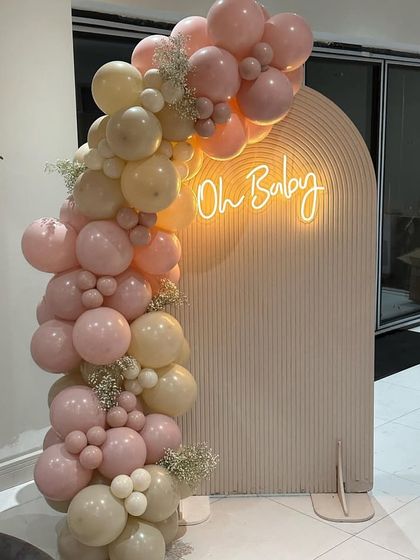 A soft and elegant 'Oh Baby' backdrop in pastel pink. The organic balloon garland with baby's breath flowers adds a delicate and beautiful touch to this baby shower decor.