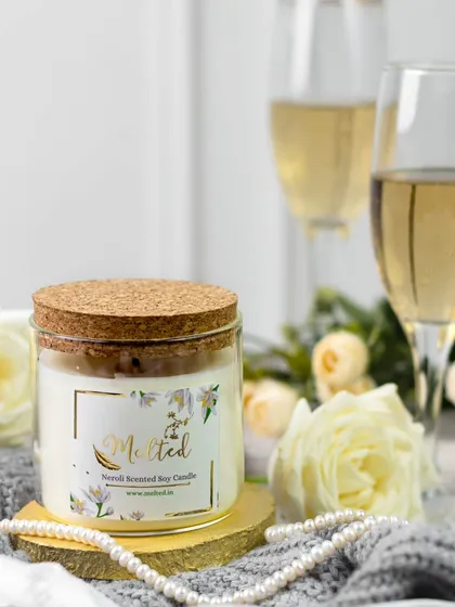 Styled to whisper elegance. This shot focuses on the clean design of the candle, surrounded by soft whites, golden tones, and cozy textures that tell a quiet story of luxury and comfort.