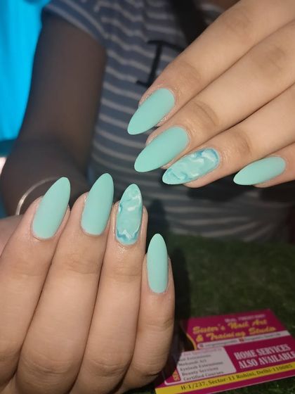 A chic and modern matte look. These almond-shaped nails are a solid mint green with a single accent nail featuring a matching marble design.