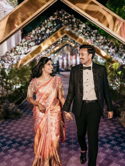 The couple making their grand entrance at the reception, walking hand-in-hand down a beautifully lit pathway.