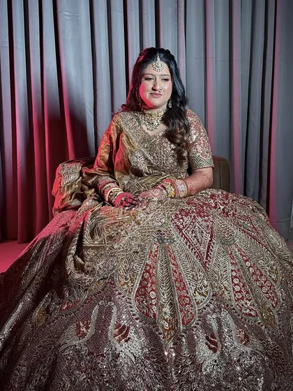 A full-length portrait showcasing the bride's magnificent, heavily embroidered lehenga. The makeup provides a perfect balance to the opulent outfit.