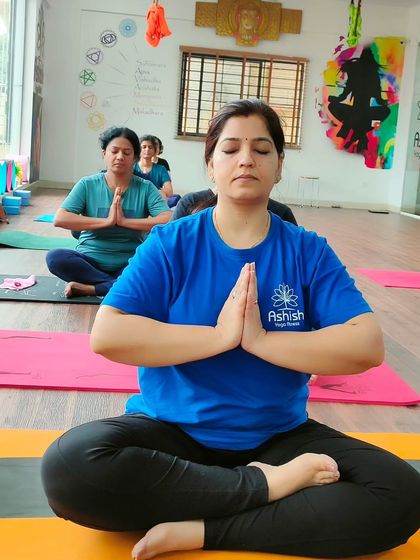 A student in a seated meditative pose with hands in Anjali Mudra (prayer position), finding her center.