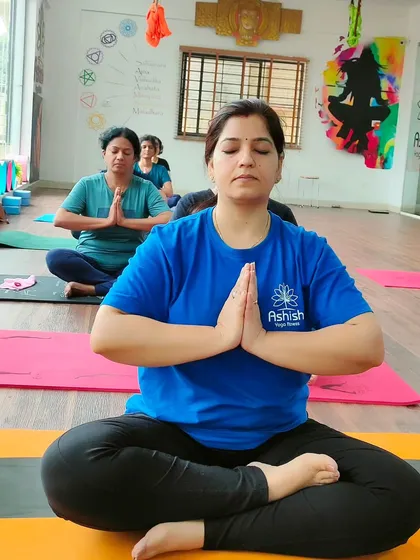 A student in a seated meditative pose with hands in Anjali Mudra (prayer position), finding her center.