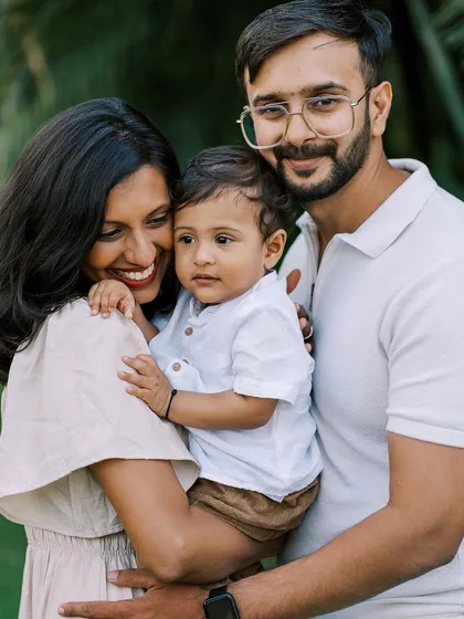 A happy family portrait, with the mother and father smiling at the camera and their son looking sweet and content.