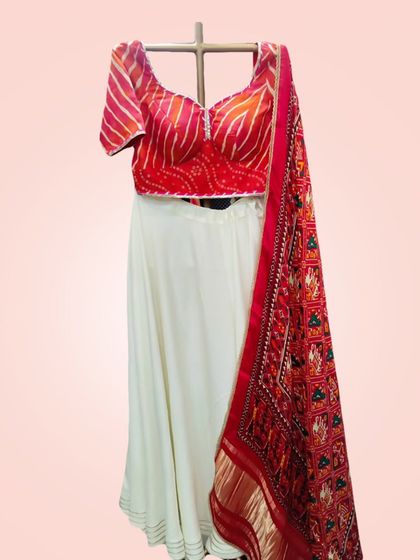The full white and red lehenga set on a mannequin, showcasing the beautiful contrast between the plain skirt and the richly printed dupatta.