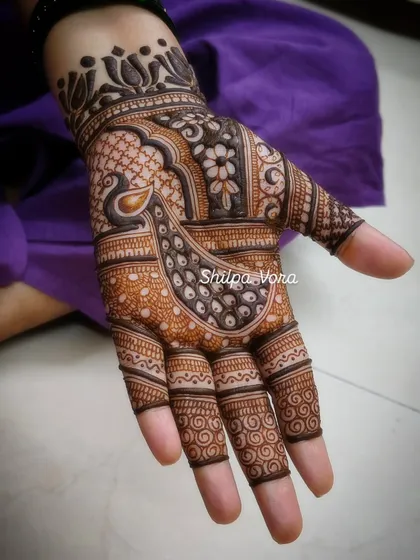 A beautiful peacock-themed design for Karwa Chauth, with the bird's feathers flowing across the hand.
