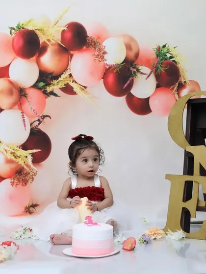 An elegant first birthday setup featuring a red, pink, and gold color palette. These sessions are perfect for creating classic and beautiful one-year-old portraits before the cake smash begins.
