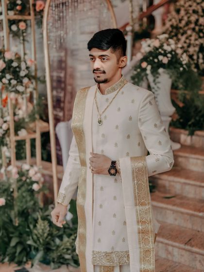 A stylish groom in his traditional attire, posing before the wedding ceremony begins.