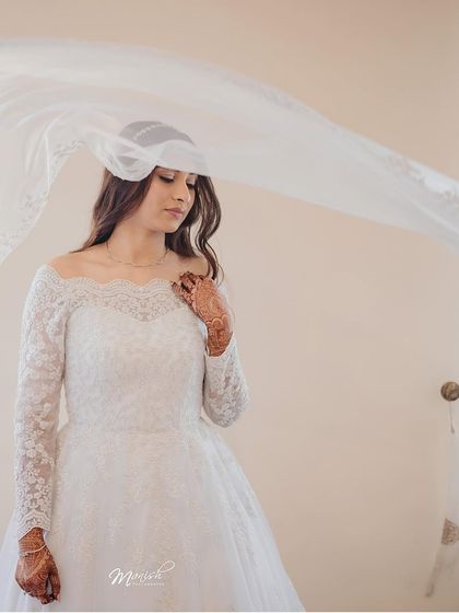 An ethereal portrait of the bride with her veil flowing in the wind, creating a soft and dreamy wedding day image.