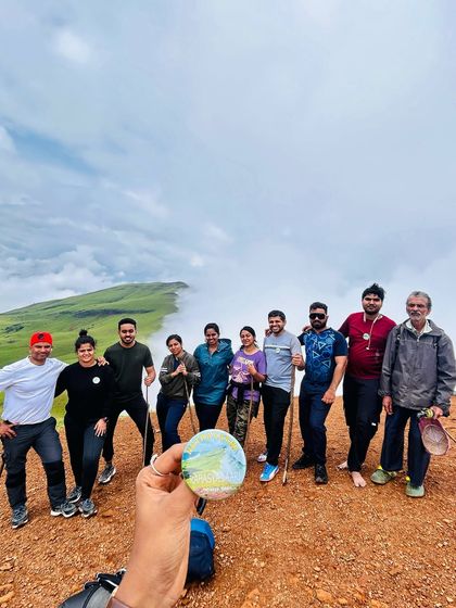 Our group on the reddish-brown trail near the Kudremukha peak, with a sea of clouds behind them.
