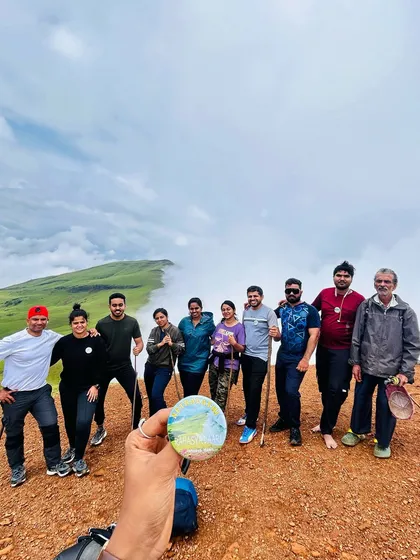 A fun group photo on the reddish-brown trail of a Kudremukha peak, with a sea of clouds behind us. The contrast of colors is a unique feature of this trek.