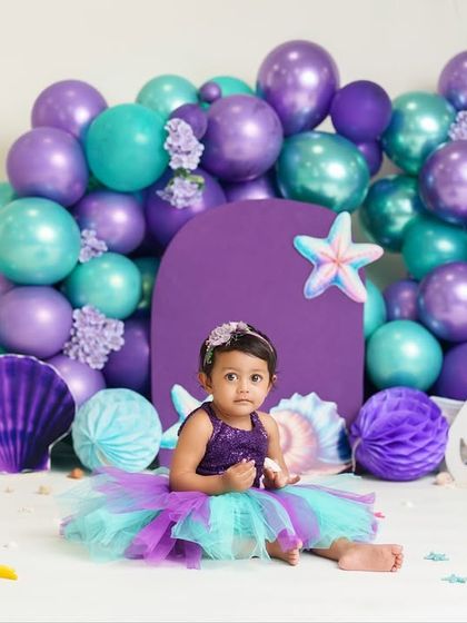 A full view of the enchanting mermaid-themed first birthday setup. The purple and teal colors create a beautiful under-the-sea atmosphere.