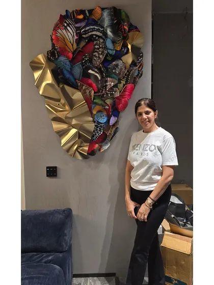 The happy client standing next to her new custom butterfly wall sculpture.