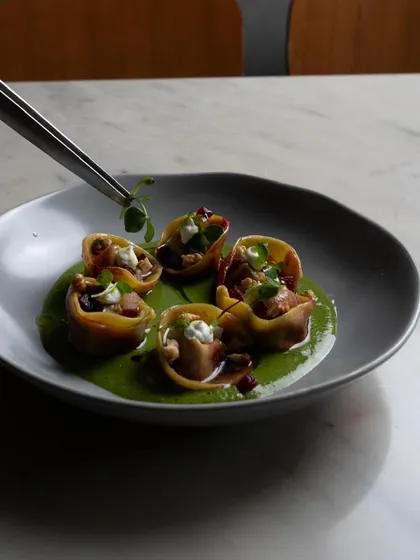 The final touch of a microgreen garnish being placed on our Beetroot Tortellini with tweezers, showcasing our attention to detail.