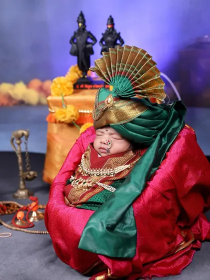 The same newborn, now adorned with a traditional pheta (turban), adding a touch of royalty to the divine theme.