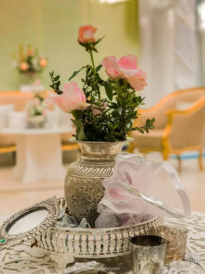 A close-up of a silver tray with an ornate vase and mirror, reflecting the soft and elegant details of the pastel Haldi decor.