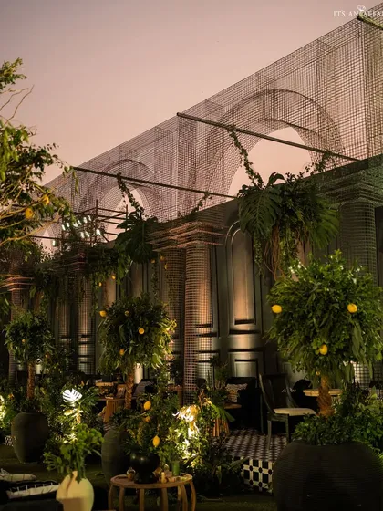 The 'Lemon Garden' setup at dusk, with warm lighting highlighting the rows of potted lemon trees and intricate mesh arch structures.