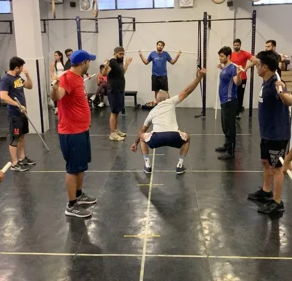 A coach demonstrates a deep squat position during a mobility warm-up for our weightlifting seminar. Proper mobility is key to achieving depth and stability in lifts like the snatch and clean.