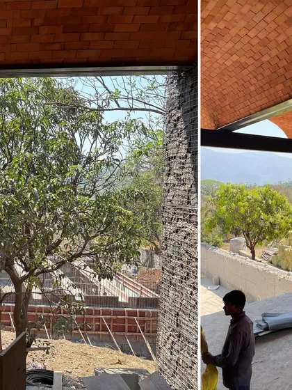 A view from within the Karjat residence, where the line between the built space and the natural world is blurred. The brick arches frame the landscape, drawing the eye outwards towards the distant hills.