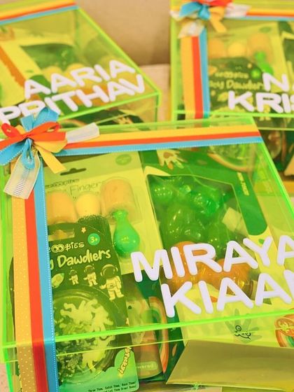 A vibrant neon green acrylic box hamper filled with goodies. These personalised boxes are perfect for creating eye-catching return gifts for a neon themed party.