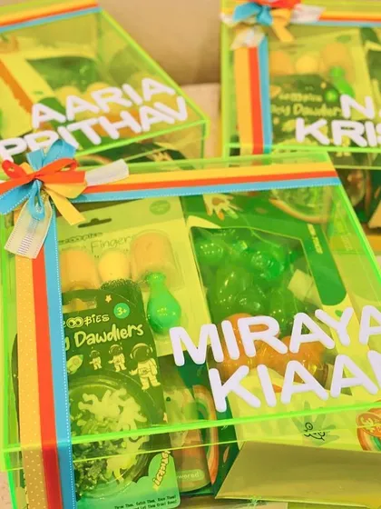 A vibrant neon green acrylic box hamper filled with goodies. These personalised boxes are perfect for creating eye-catching return gifts for a neon themed party.