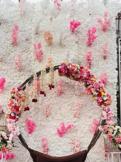 A beautiful photo corner featuring a circular swing decorated with flowers, set against a wall of white and pink florals.