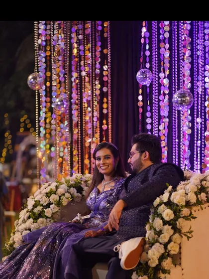 A couple enjoying a quiet moment during their reception. The backdrop of shimmering purple sequins and disco balls creates a glamorous and celebratory atmosphere.