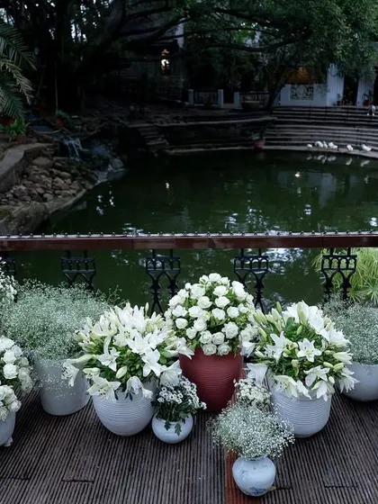 White floral arrangements in terracotta pots line the bridge over the Kalyani, blending rustic and elegant decor styles.