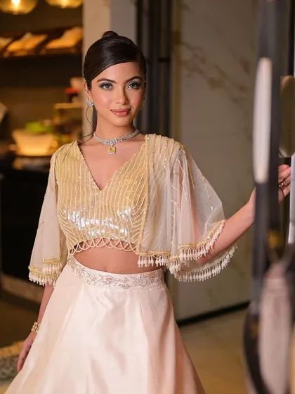A super glam cocktail look that combines a shimmering outfit with a bold, creative eye look. The pop of blue liner and face gems add a touch of modern artistry.