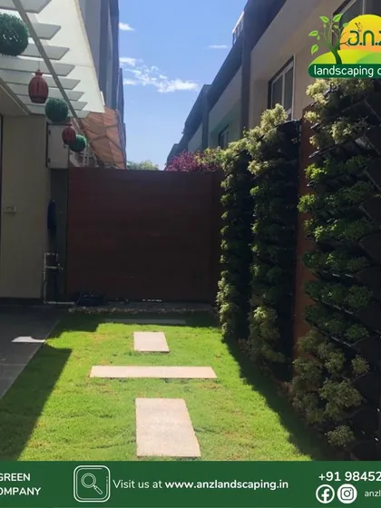 A duplicate of media ID 6. A daytime perspective of the residential courtyard, looking down the lawn path. The vertical gardens on the side add privacy and greenery without sacrificing valuable floor space in this narrow outdoor area.