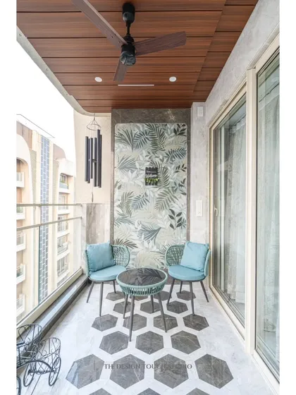 A dedicated seating nook on the balcony, with a tropical-themed wall panel that adds a touch of nature and serenity. The wind chimes complete the peaceful ambiance.