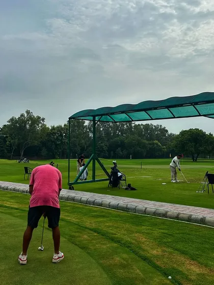 A golfer practices on the putting green, which is conveniently located right next to the main driving range.