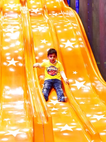 A young boy enjoying the ride down our star-studded slide. Our play areas are designed to be visually engaging and exciting for children.