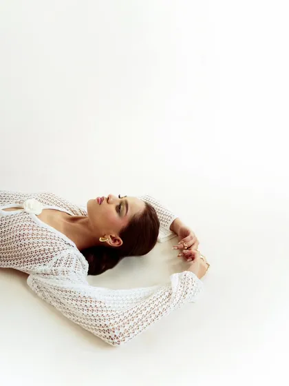 An ethereal, high-key shot featuring a white mesh dress. The model's reclining pose and the bright, airy lighting create a dreamy and serene mood.