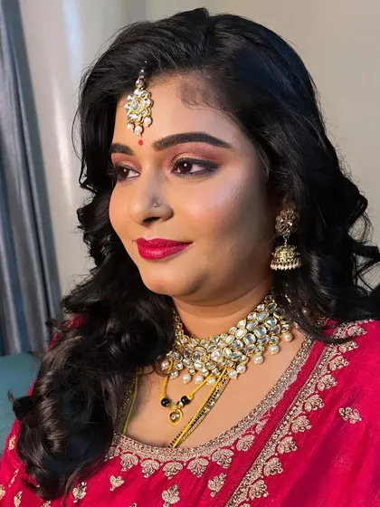 A close up of Divya's makeup. The focus is on her expressive eyes, enhanced with a classic winged liner, and a perfectly applied bold red lipstick.