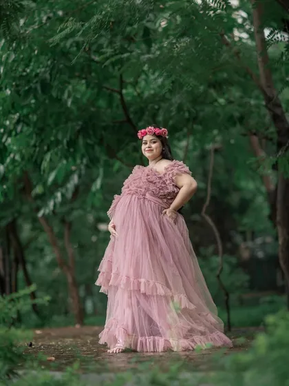 A full-length shot of the dusty rose gown, showing its tiered ruffles and how it flows beautifully in a woodland setting.